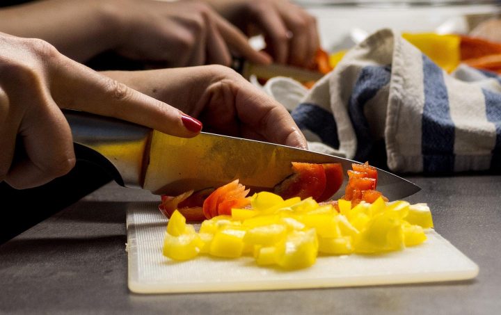 Una mano cortando un pimiento morrón