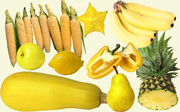 Una variedad de frutas y verduras amarillas, incluyendo calabacín, manzana, pera, piña, pimiento, plátanos, limones, carambola y maíz.