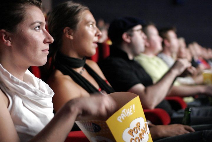 Una mujer comiendo palomitas en un cine 
