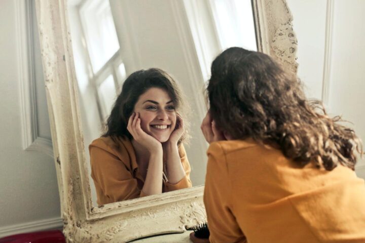 Una mujer se mira al espejo con una sonrisa positiva