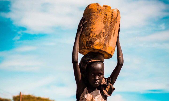 Una niña africana llevando agua a su casa